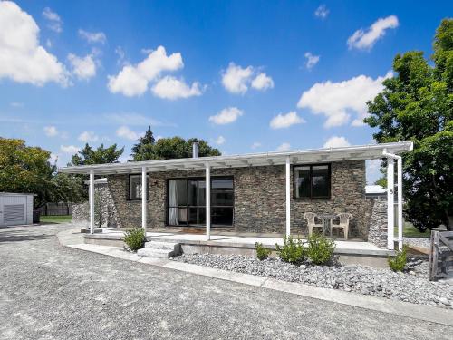 a small stone house with a porch at Hallewell Haven in Twizel