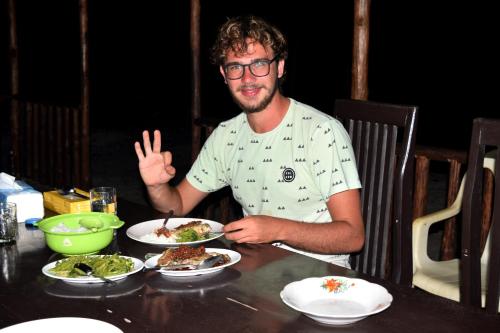 a man sitting at a table with a plate of food at Tanjung Kalemo Resort in Batudaka