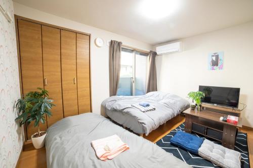 1 dormitorio con 2 camas, escritorio y TV en ミニマリズムホテル葛飾 en Tokio