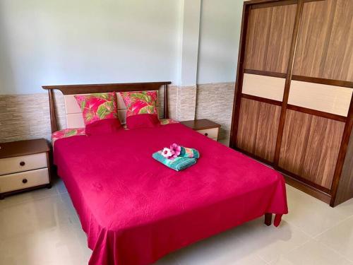 a bedroom with a red bed with a pink blanket at Taina - Terrasse - Bord de mer - in Opoa