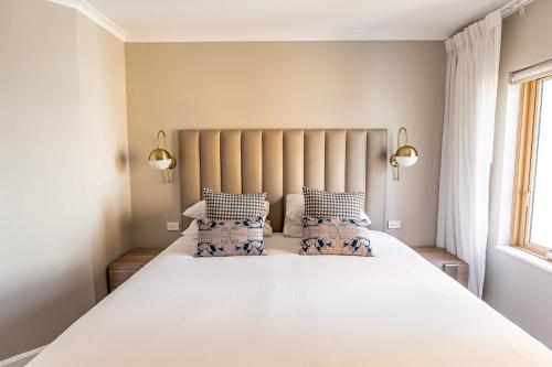 a bedroom with a large white bed with two pillows at The Sebel Quay West Suites Sydney in Sydney