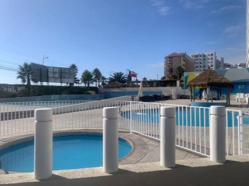 a swimming pool with a white fence next to it at Departamento frente al mar YMAS in La Serena