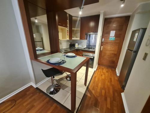 a small kitchen with a table and a refrigerator at San Ignacio Suite Apartments in Santiago