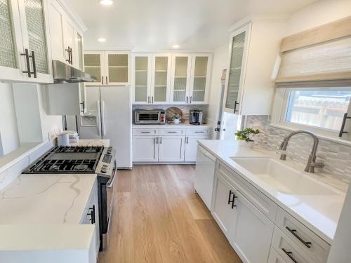 a kitchen with white cabinets and a sink at El Nido Beachlife Cottage in South Bay Los Angeles in Redondo Beach