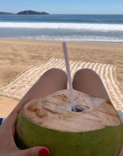 a person holding a green coconut with a stick in it at Villa Polinesia Chamela in Pérula