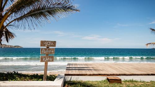 a beach with a wooden boardwalk and the ocean at Villa Polinesia Chamela in Pérula