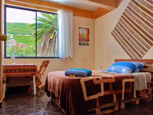 a bedroom with a bed with a window and a table at La Casita Feliz...!!! in Cochabamba