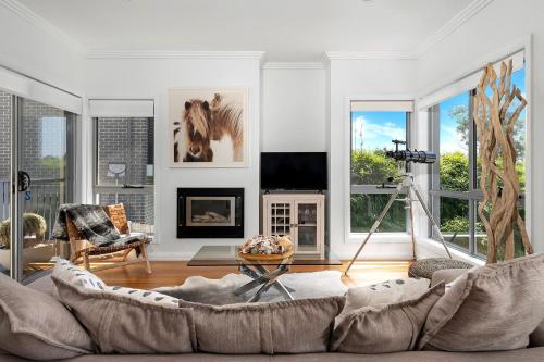 a living room with a couch and a horse on the wall at Sapphire on Wilson Gerringong in Gerringong