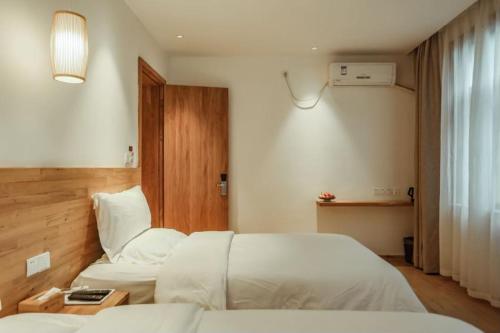 a hotel room with two beds and a window at Villa EN Emerald Valley, Huangshan in Huangshan Scenic Area