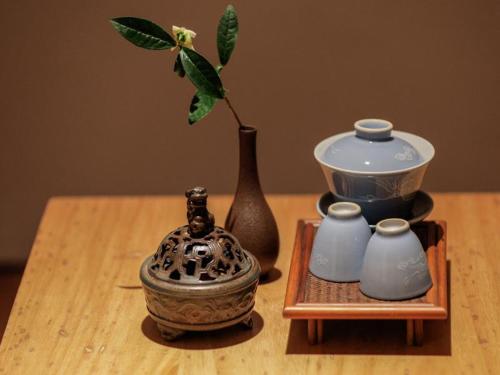 a wooden table with a vase and a pot with a plant at Villa EN Emerald Valley, Huangshan in Huangshan Scenic Area
