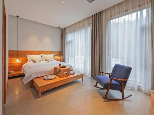 a bedroom with a bed and a blue chair at Villa EN Emerald Valley, Huangshan in Huangshan Scenic Area