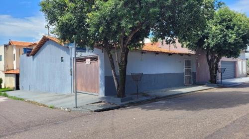 a blue house with a tree on a street at Olga Moreira 01 - inclui garagem in Paragominas