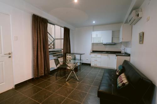 a living room with a couch and a table and a kitchen at LM Hoteles in Piura