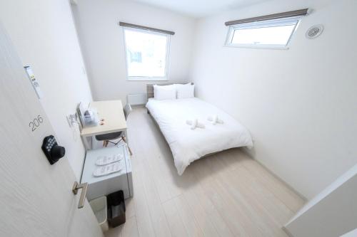 Jest to niewielki, biały pokój z łóżkiem i biurkiem. w obiekcie JL HOUSE Kutchan w mieście Kutchan