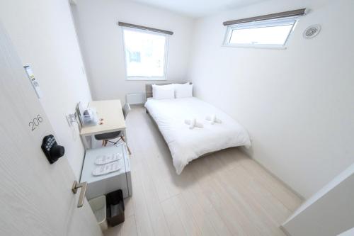 俱知安町JL HOUSE Kutchan的白色的小房间,配有床和书桌