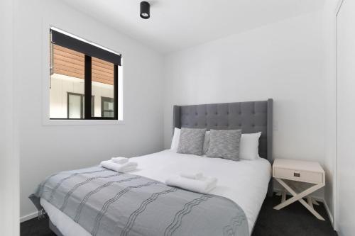 a white bedroom with a large bed and a window at Skyline Suite in Queenstown