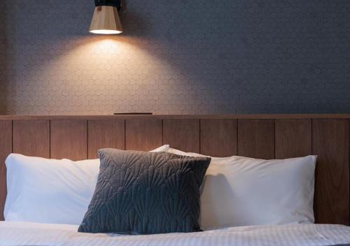 a bed with white pillows and a light above it at Miyako Daiichi Hotel in Miyako Island