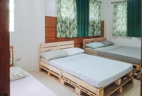 two beds in a room with green curtains at RedDoorz @ Balai Baibai Cagayan in Bawa