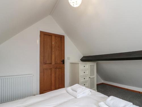 a bedroom with a white bed and a wooden door at Stable Cottage in Whitby