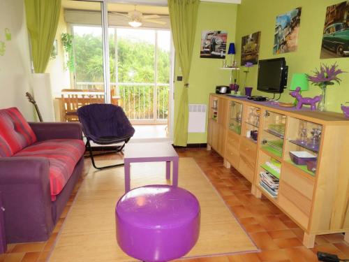 un salon avec un canapé violet et une télévision dans l'établissement Studio cabine à Sète avec terrasse, parking et proche plage - FR-1-338-375, à Sète