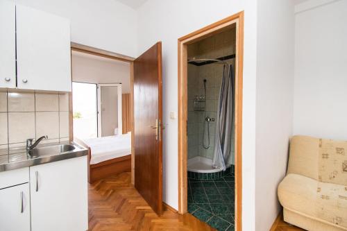 a kitchen with a sink and a bathroom with a shower at Apartments More Sunce in Seline