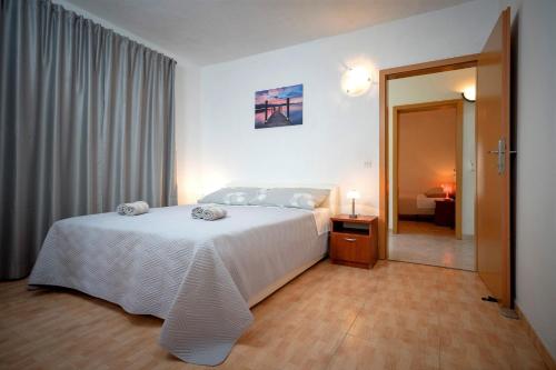 a bedroom with a large white bed and a room with a bed sqor at House Peacefull Relax in Zastražišće