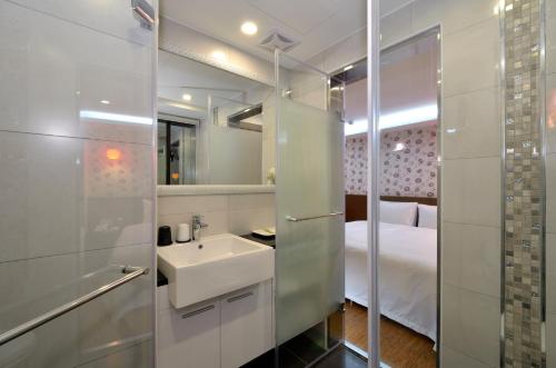 ein Bad mit einem Waschbecken und einem Bett in der Unterkunft Hua Da Hotel- Nanxi in Taipeh