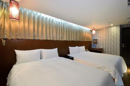 2 Betten in einem Hotelzimmer mit weißer Bettwäsche in der Unterkunft Hua Da Hotel- Nanxi in Taipeh