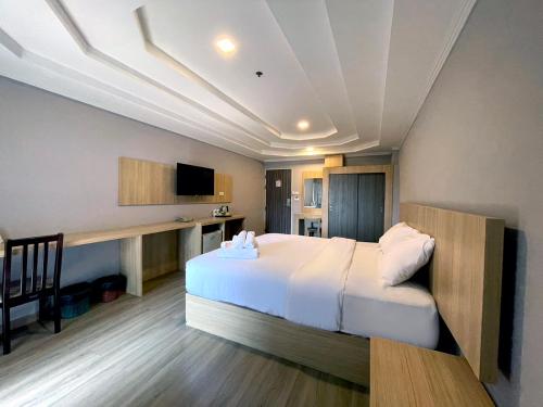 una camera con un grande letto e una TV di Tara Garden Hotel a Bangkok