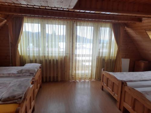 - une chambre avec 2 lits et une grande fenêtre dans l'établissement Antal Villa - 5mins to ski slope & 1min to skating, à Harghita-Băi