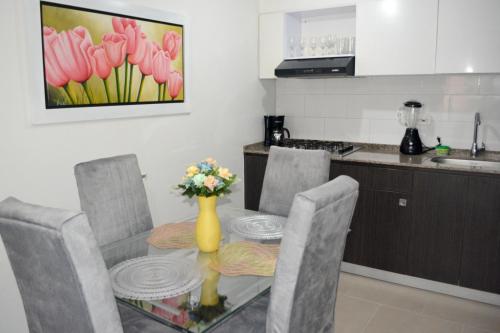 una mesa de comedor con sillas y un jarrón de flores en Acogedor apartamento vacacional en zona centrica de Ibague, en Ibagué