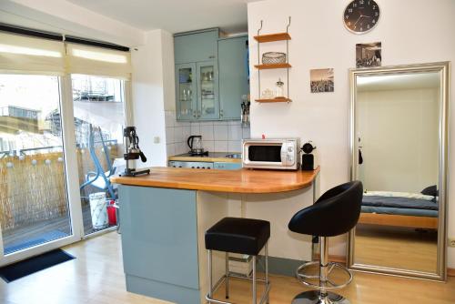 eine Küche mit einer Theke mit einer Mikrowelle und 2 Barhockern in der Unterkunft Appartment mit großem Balkon im belgischen Viertel in Köln