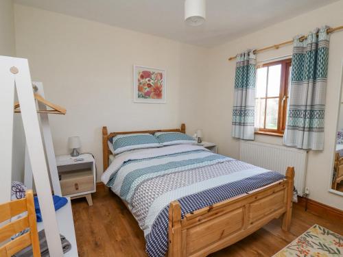 ein Schlafzimmer mit einem Bett und einem Fenster mit Vorhängen in der Unterkunft Beudy in Cardigan