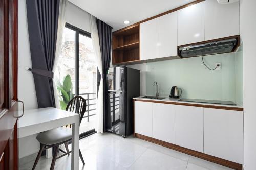 a kitchen with white cabinets and a table and a window at Spring Hill Apartment -The High Class in Ho Chi Minh City