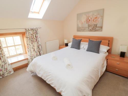 a bedroom with a large white bed and a window at Low Croft in Alnwick