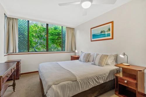 a bedroom with a bed and a desk and windows at Fuller Holidays-Unit Pacific in Byron Bay
