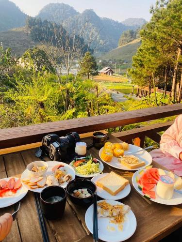 a table with plates of food on a table with a view at The Nordic Village - Evergreen Retreat in Mộc Châu