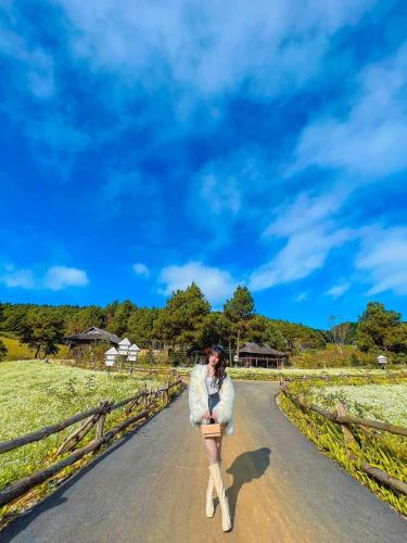 a man walking down a road in a coat and boots at The Nordic Village - Evergreen Retreat in Mộc Châu