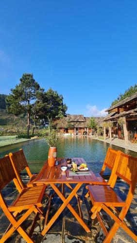a wooden picnic table with two chairs and water at The Nordic Village - Evergreen Retreat in Mộc Châu