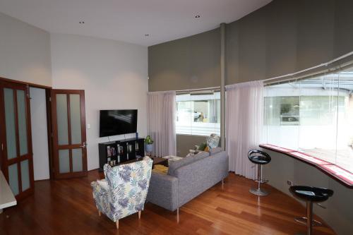 a living room with a couch and a tv at Margaret River Mainstreet Apartment in Margaret River Town