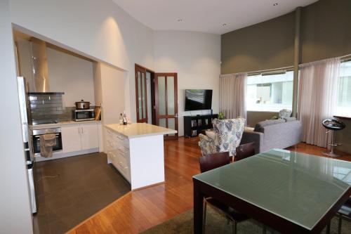a living room with a table and a kitchen at Margaret River Mainstreet Apartment in Margaret River Town