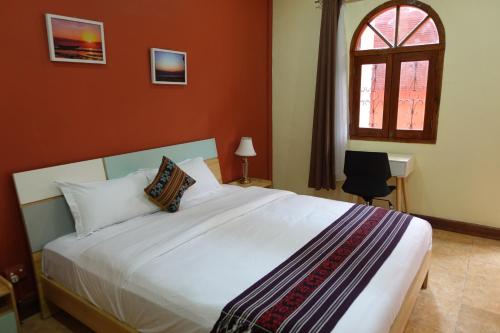 a bedroom with a large white bed with a window at Sunset INN by Pro-Ema in Dili