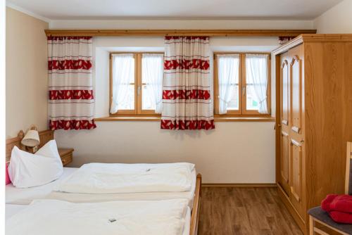 a bedroom with two beds and two windows at Gästehaus Hinterponholz in Ramsau