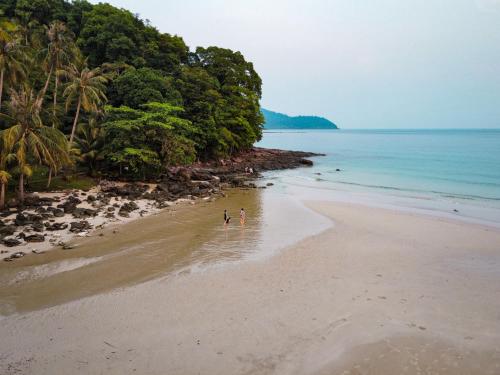 two people walking on a beach near the ocean at À La Koh Kood Resort in Ko Kood