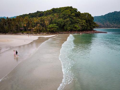 two people walking on a beach near the water at À La Koh Kood Resort in Ko Kood