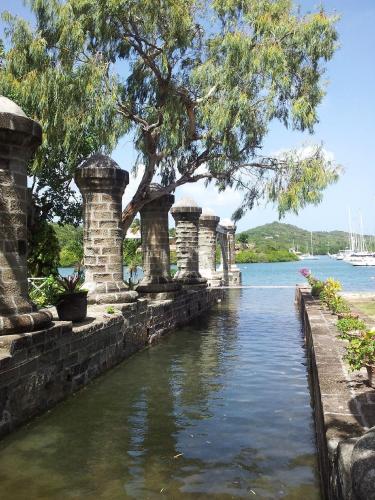 a row of stone pillars in the water with a tree at Copper and Lumber Store Hotel in English Harbour Town