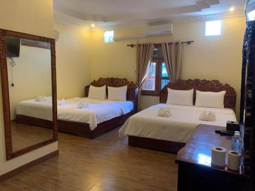 a hotel room with two beds and a mirror at Kampheak Roath Bungalows in Kampot