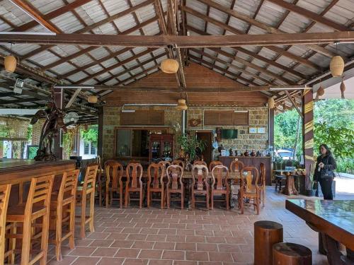 un restaurante con un bar con mesas y sillas de madera en Kampheak Roath Bungalows, en Kampot