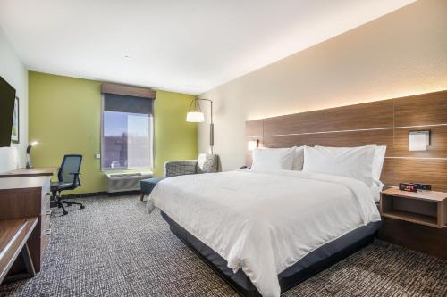 a hotel room with a large bed and a desk at Holiday Inn Express & Suites Tulsa East - Catoosa by IHG in Catoosa