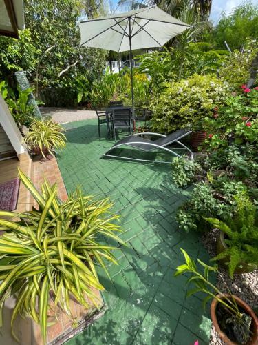 a patio with a table and an umbrella and plants at Orchid Sunset Guest House in Baie Lazare Mahé